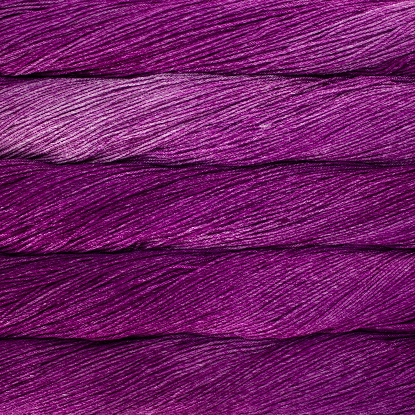 An image of skeins of Malabrigo Arroyo sport weight yarn in vibrant purple shades.