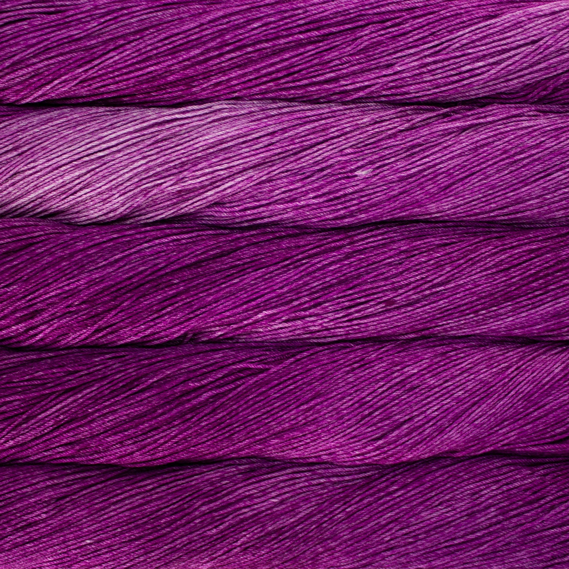 An image of skeins of Malabrigo Arroyo sport weight yarn in vibrant purple shades.