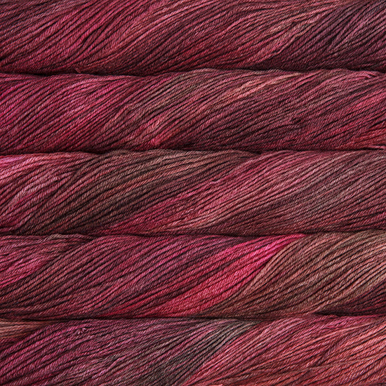 An image of skeins of Malabrigo Arroyo sport weight yarn in magenta and maroon shades.