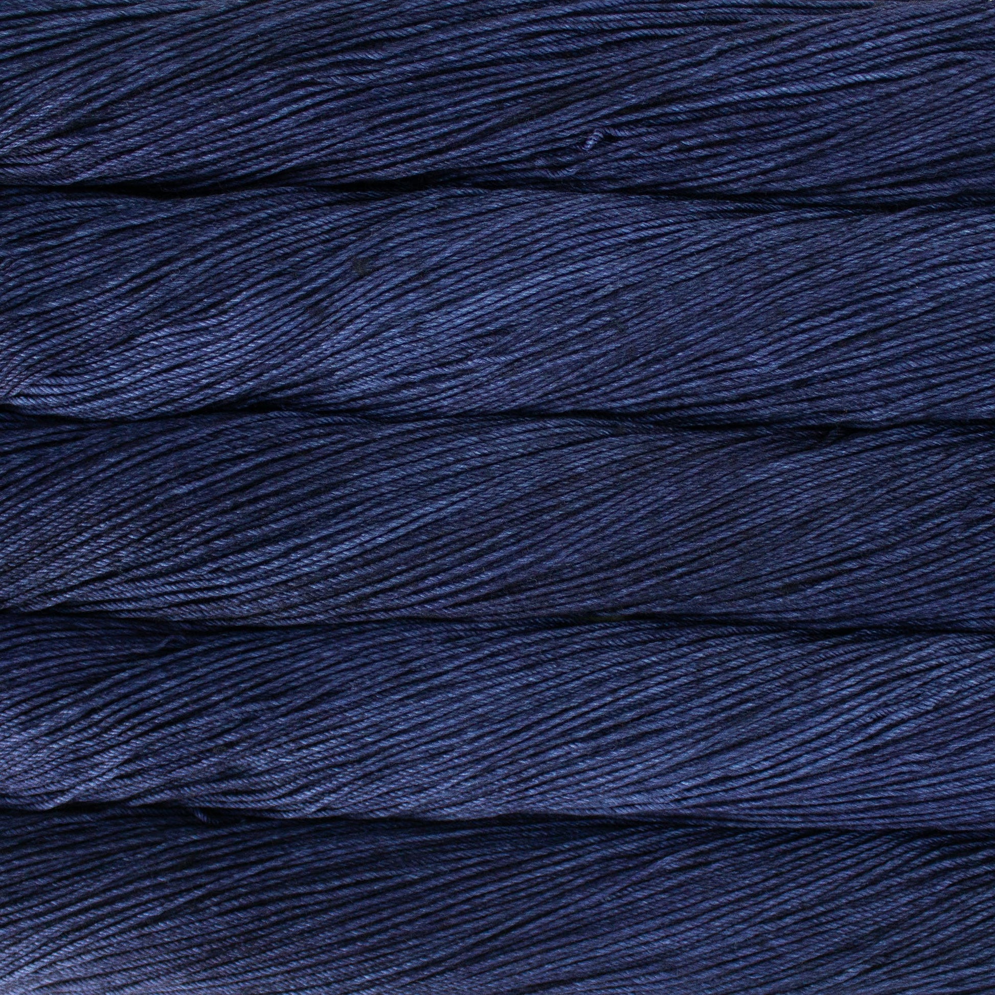 An image of skeins of Malabrigo Arroyo sport weight yarn in deep navy blue shades.