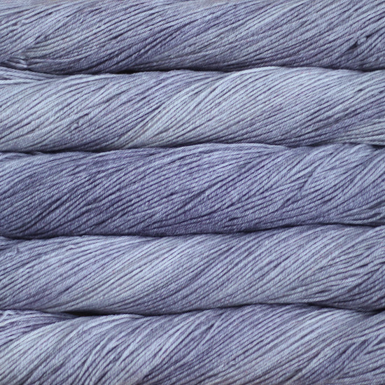 An image of skeins of Malabrigo Arroyo sport weight yarn in pale purple gray shades.
