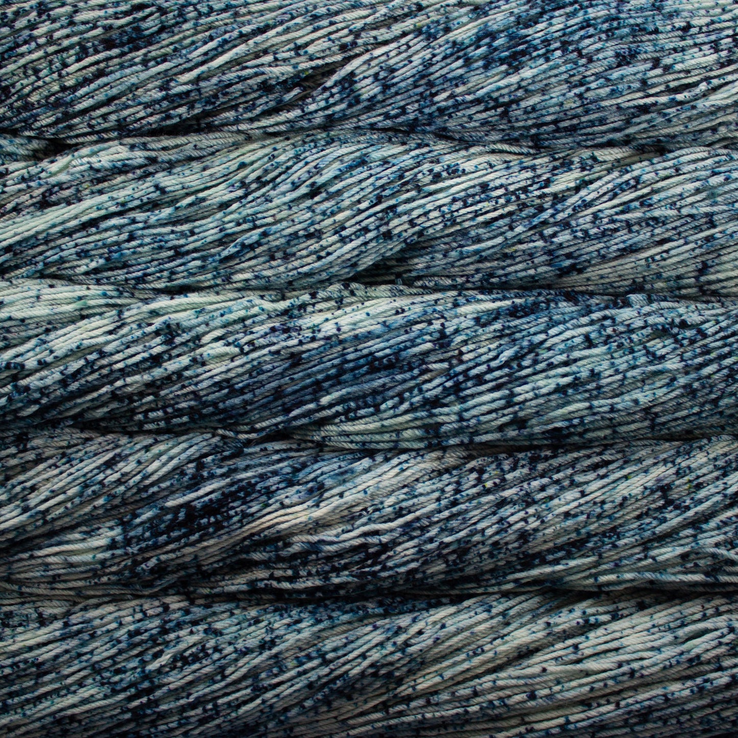 An image of skeins of Malabrigo Arroyo sport weight yarn in a light blue base with speckles of navy blue.