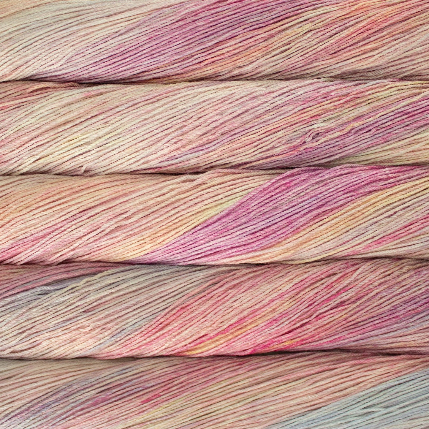 An image of skeins of Malabrigo Arroyo sport weight yarn in pastel shades of yellow, peach, pink, and gray blue.