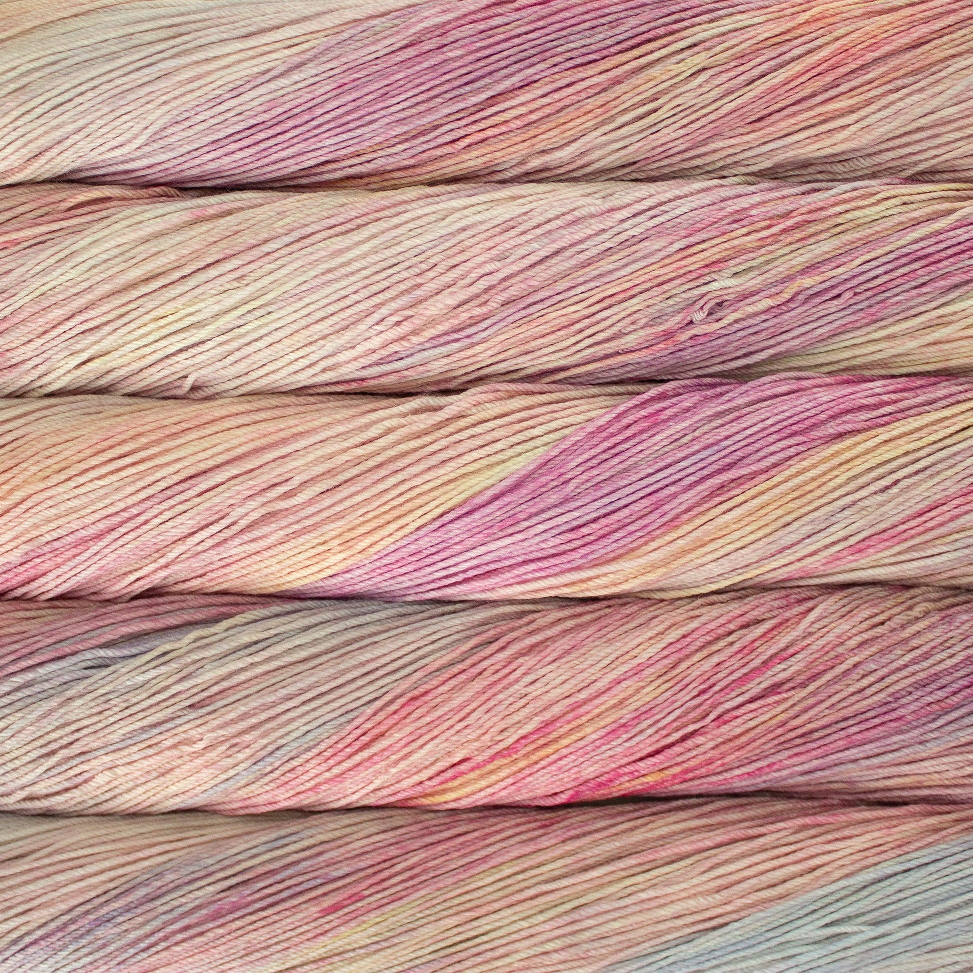 An image of skeins of Malabrigo Arroyo sport weight yarn in pastel shades of yellow, peach, pink, and gray blue.