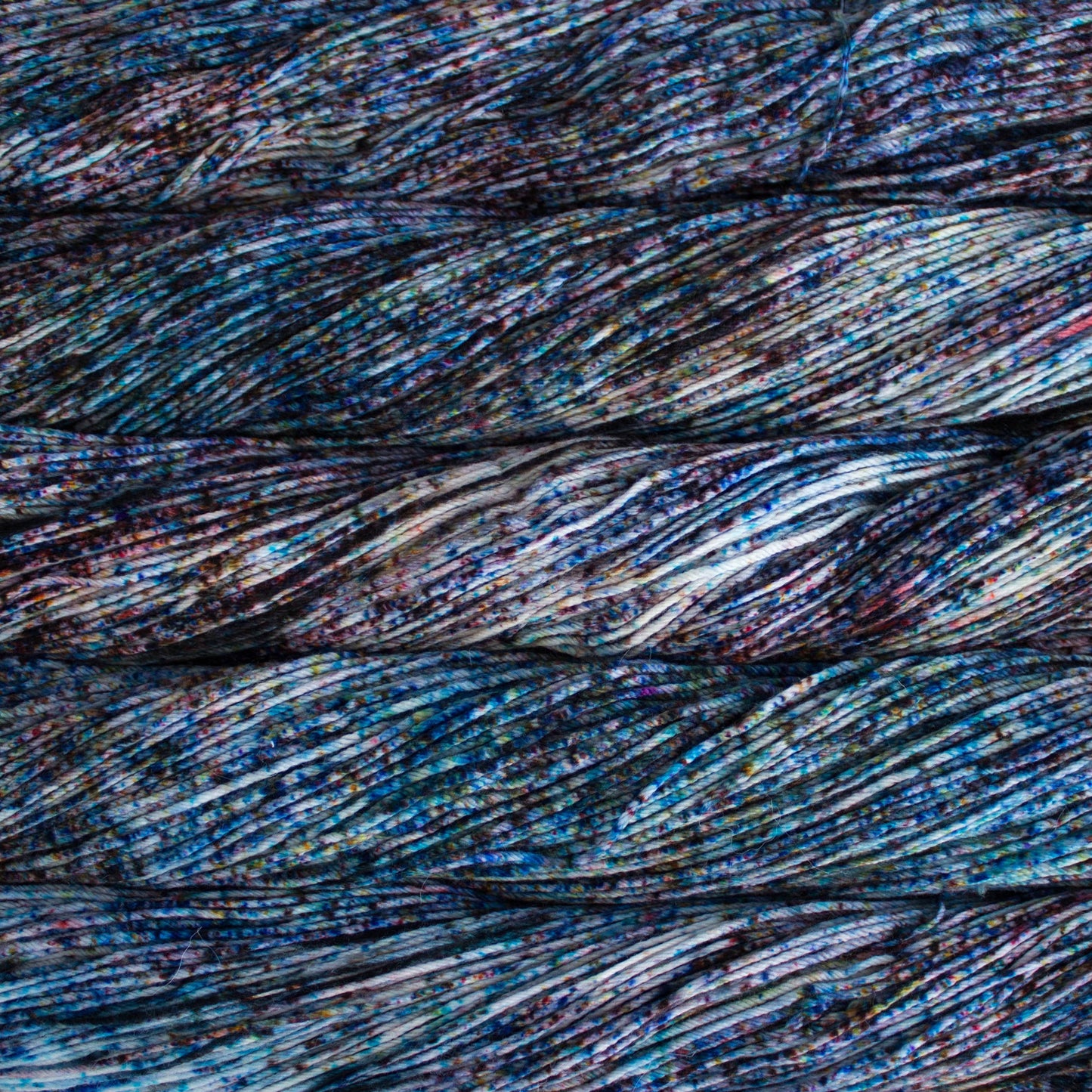 An image of skeins of Malabrigo Arroyo sport weight yarn in an off-white base with speckles of blue and purple.
