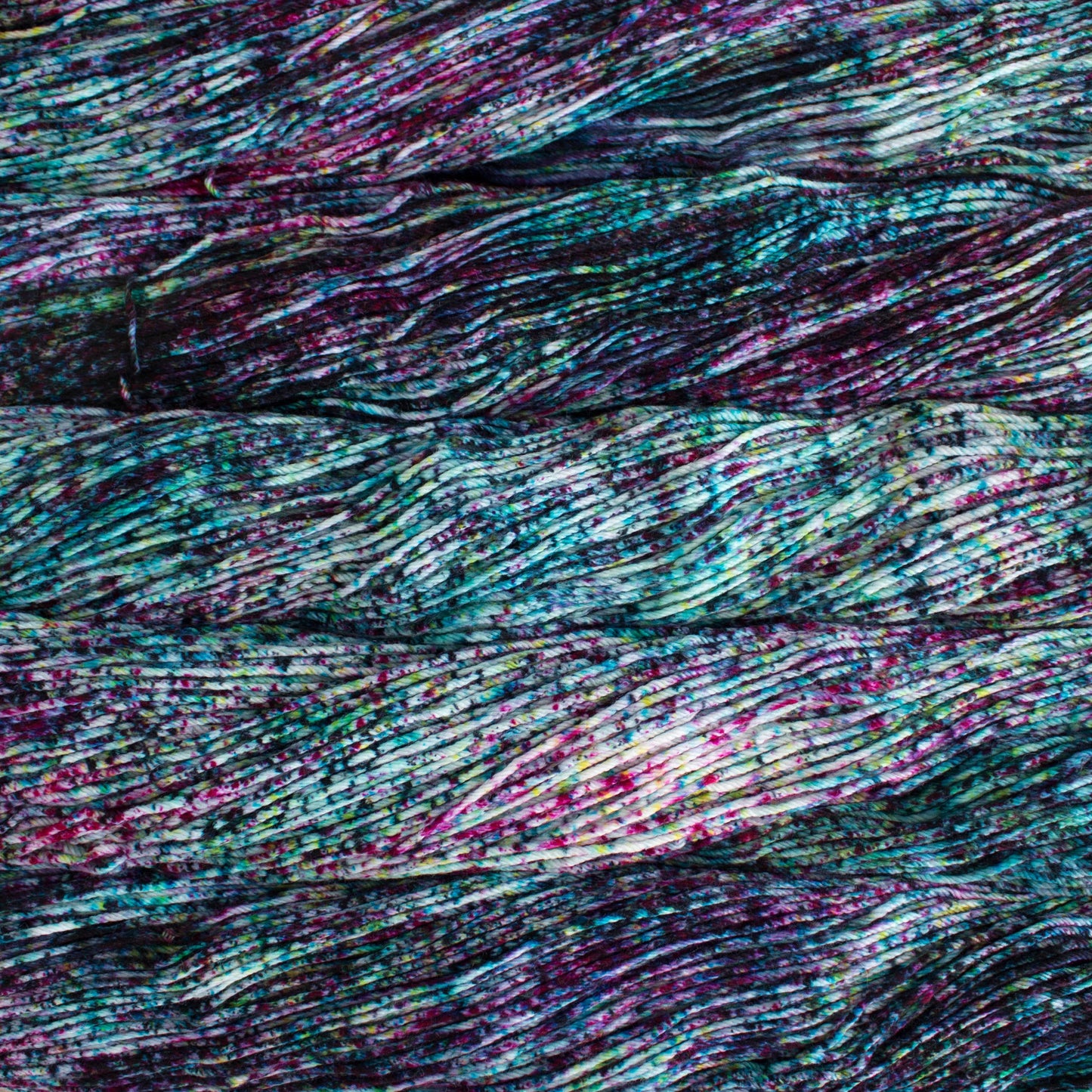An image of skeins of Malabrigo Arroyo sport weight yarn in an off-white base with speckles of teal and magenta.
