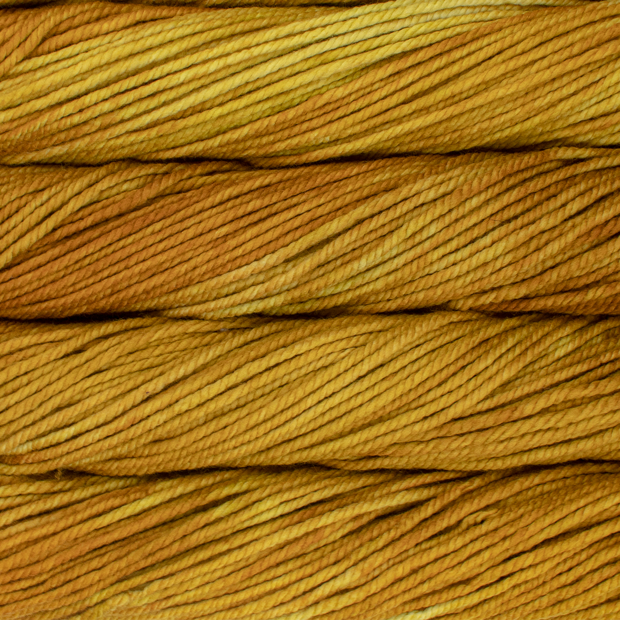 A close up image of skeins of Malabrigo Chunky bulky weight yarn in mustard yellow and gold shades.