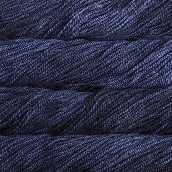 A close up image of skeins of Malabrigo Chunky bulky weight yarn in deep navy blue and charcoal shades.