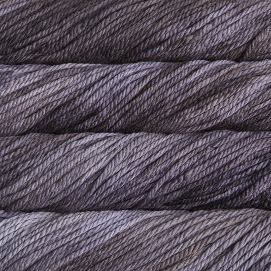 A close up image of skeins of Malabrigo Chunky bulky weight yarn in pale purple and charcoal shades.