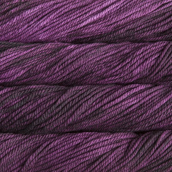 A close up image of skeins of Malabrigo Chunky bulky weight yarn in violet and dark purple shades.
