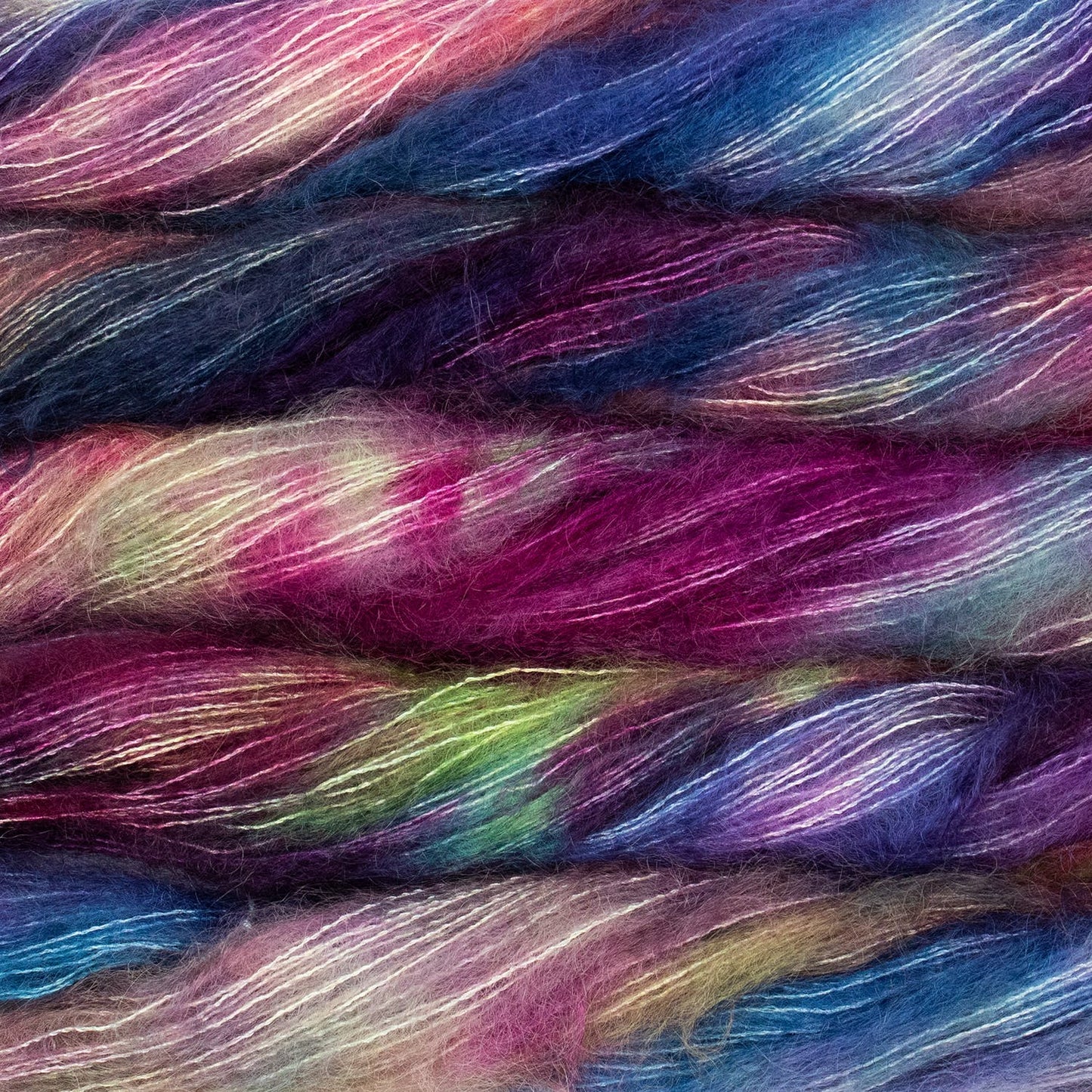 An image of multiple skeins of Malabrigo Mohair yarn in shades of blue, purple, pink, and green.