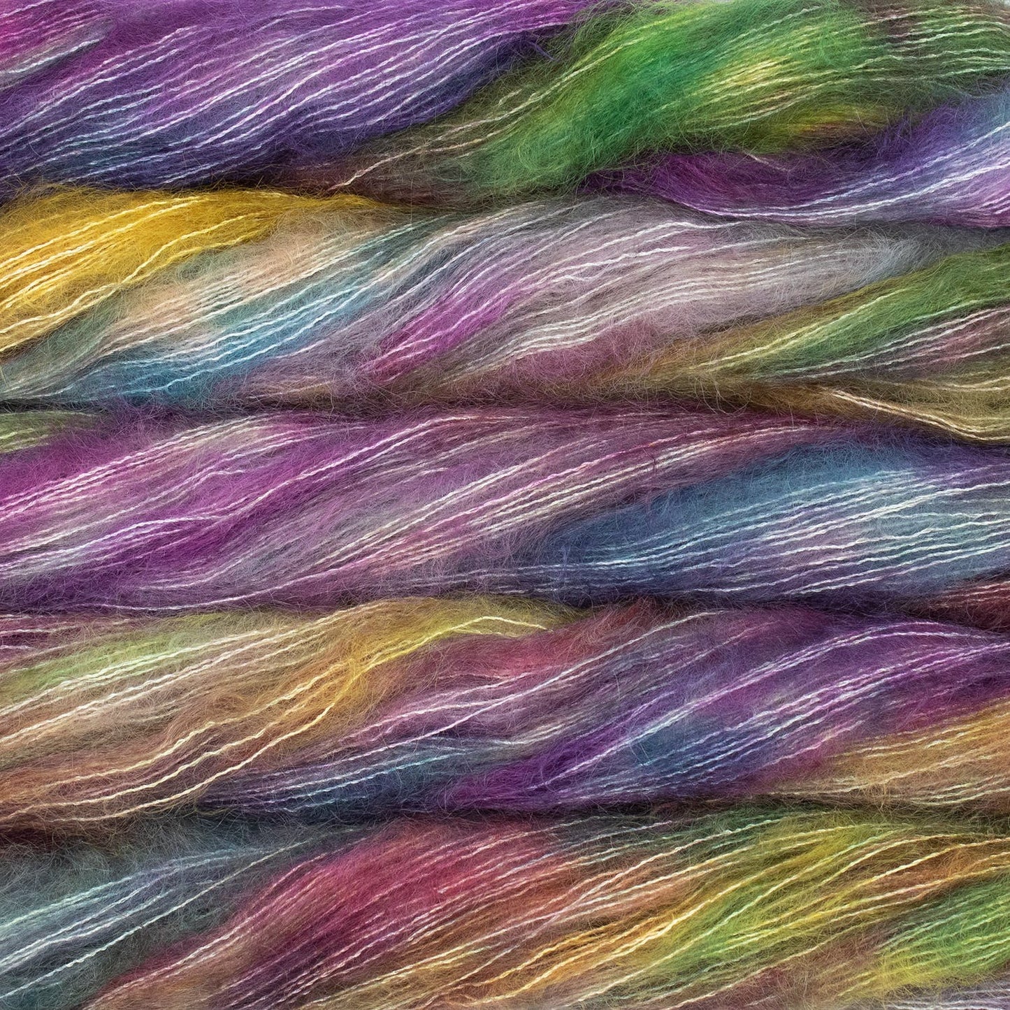 An image of multiple skeins of Malabrigo Mohair yarn in shades of purple, green, yellow, and teal.