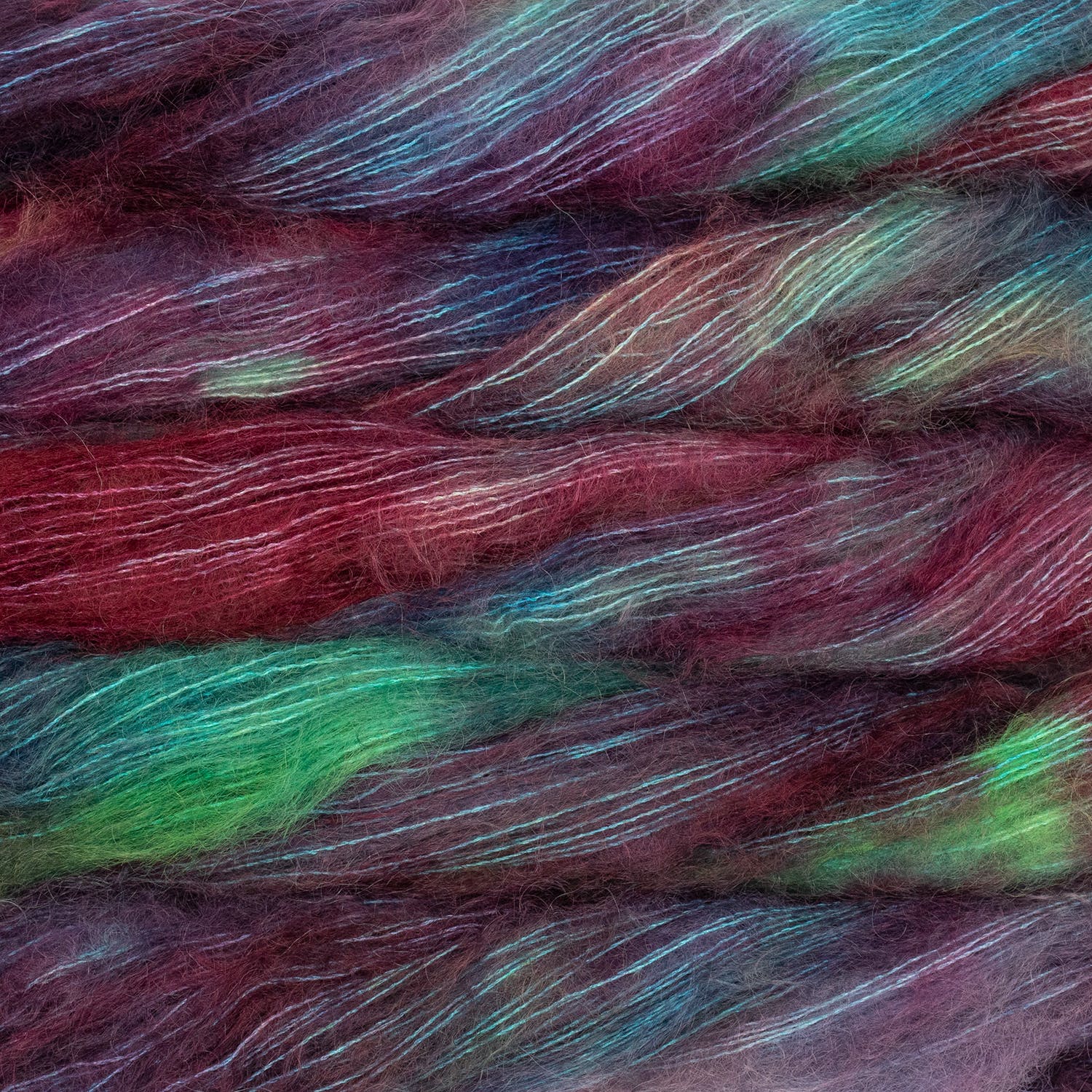 An image of multiple skeins of Malabrigo Mohair yarn in deep red, purple, aqua blue, and green shades.