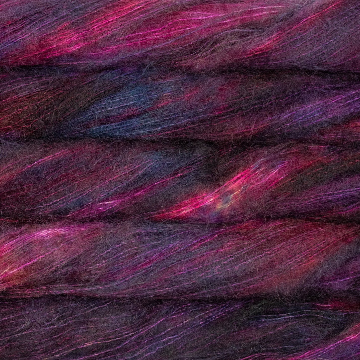 An image of multiple skeins of Malabrigo Mohair yarn in deep purple, red, and pink shades.