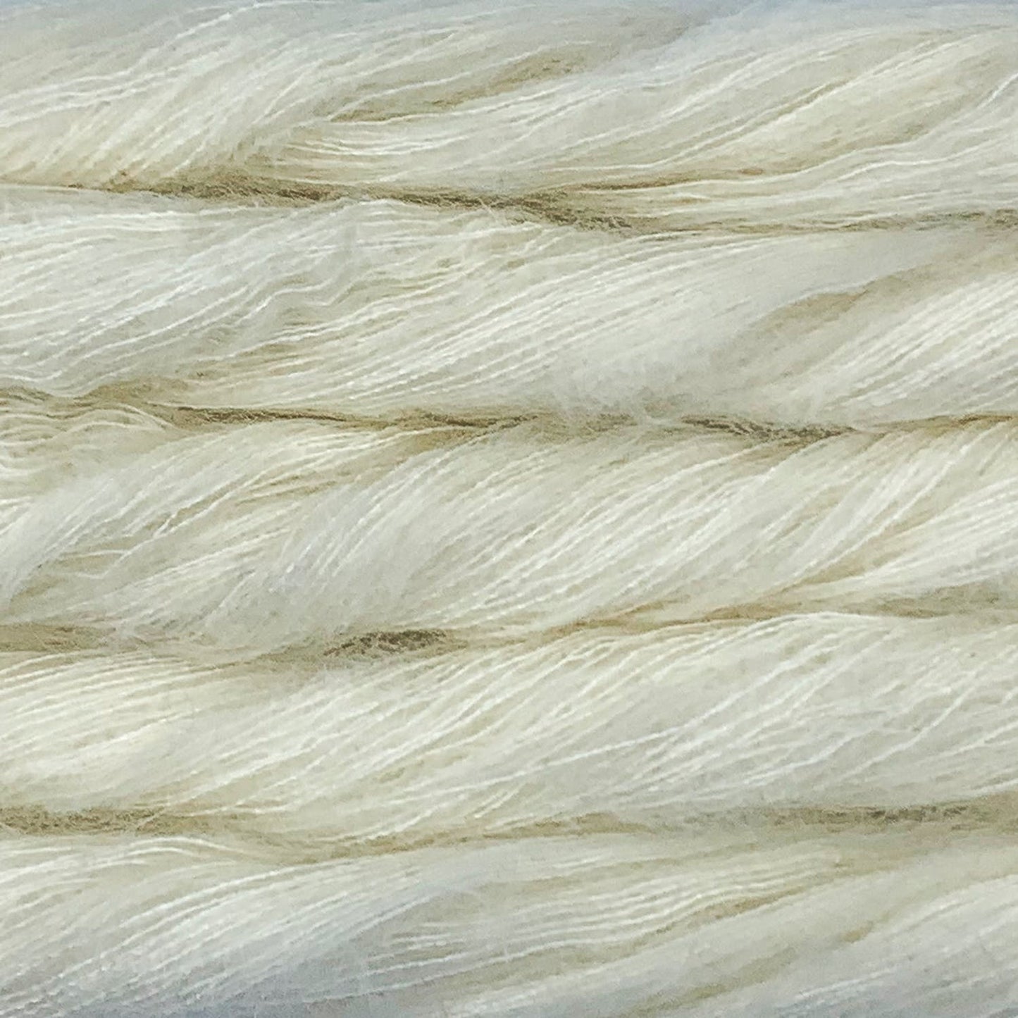 An image of multiple skeins of Malabrigo Mohair yarn in a natural off-white color.