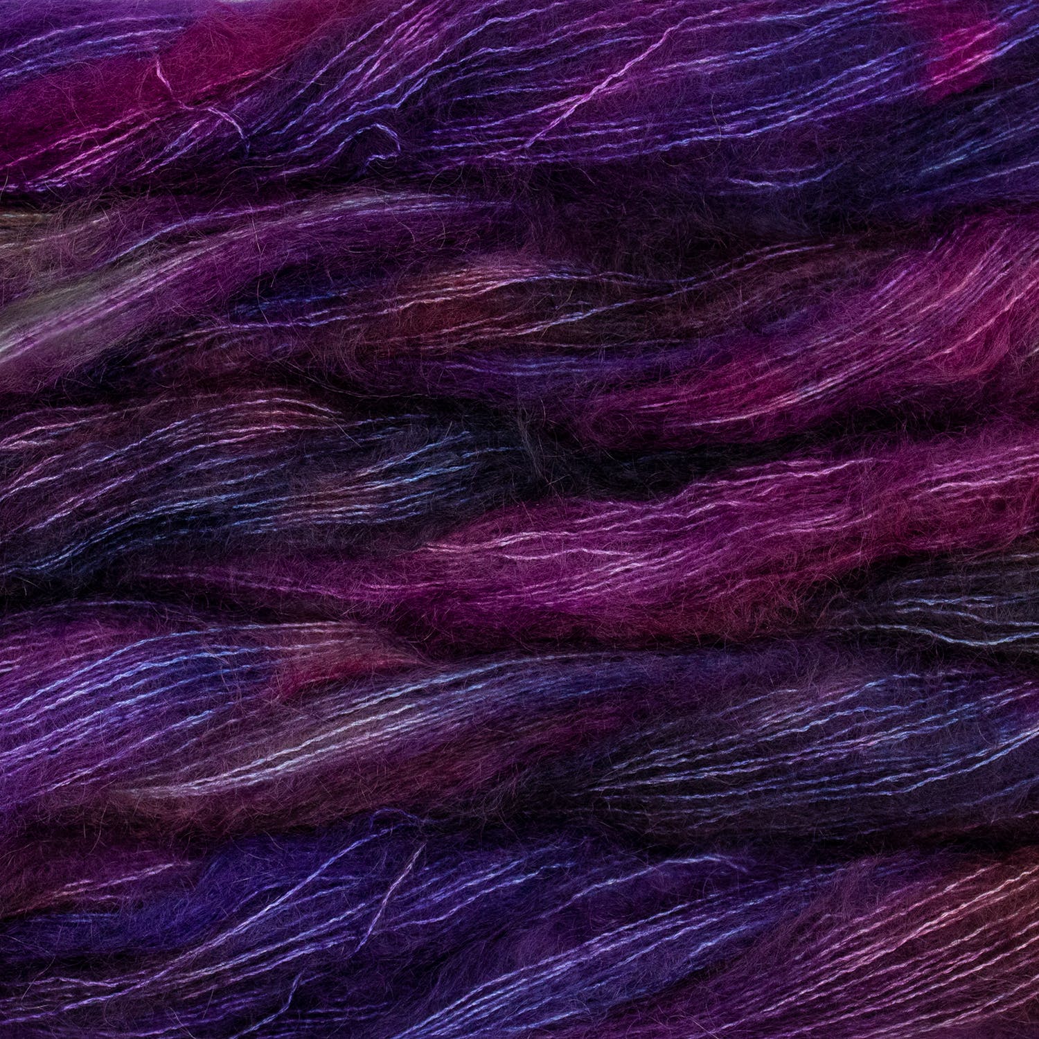 An image of multiple skeins of Malabrigo Mohair yarn in vibrant shades of purple and magenta.