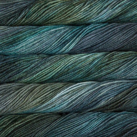 A close up of skeins of Malabrigo Rios worsted weight yarn in deep blue, green, aqua, and teal colors