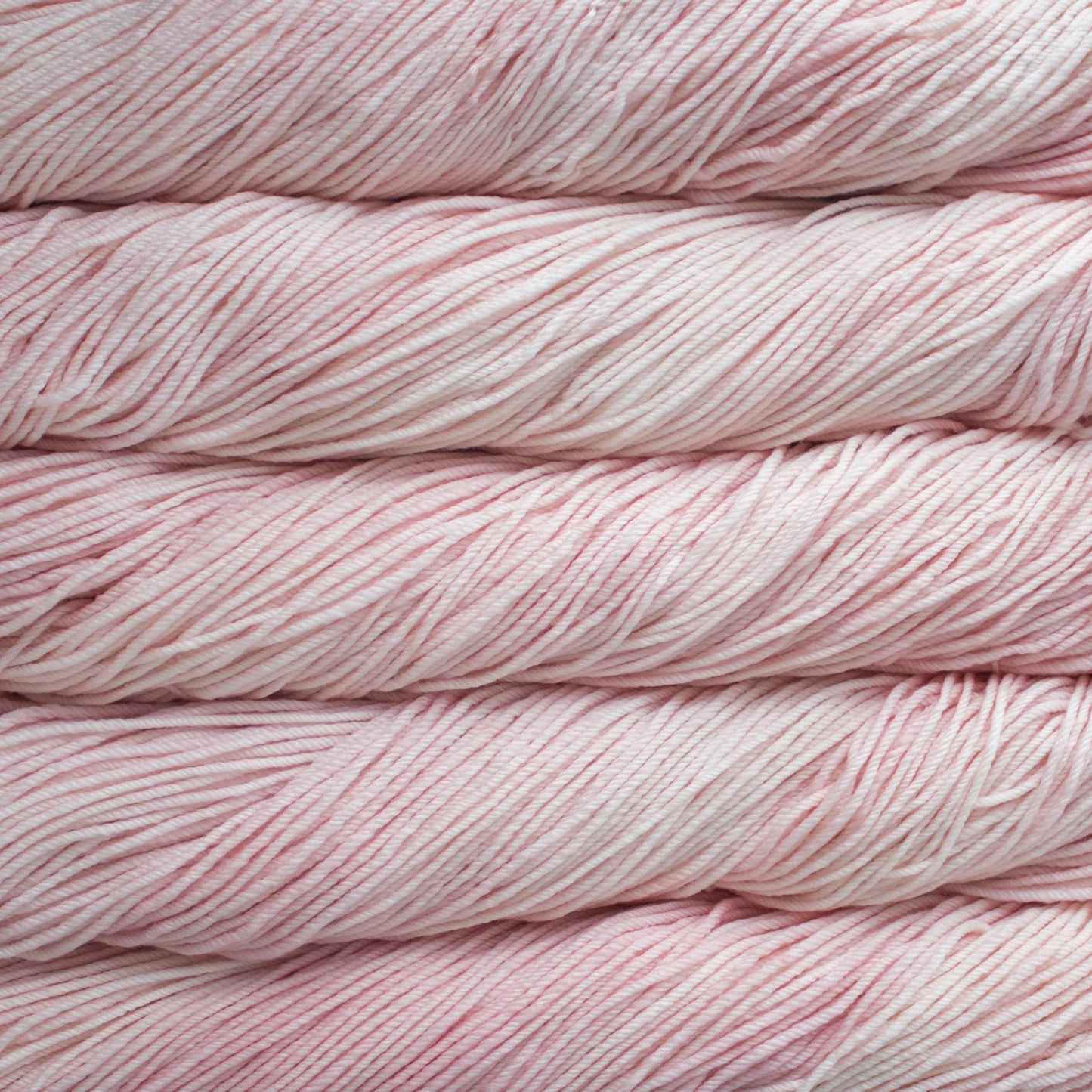 A close up of skeins of Malabrigo Rios worsted weight yarn in light pink color