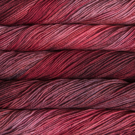 A close up of skeins of Malabrigo Rios worsted weight yarn in deep muted red and pink colors