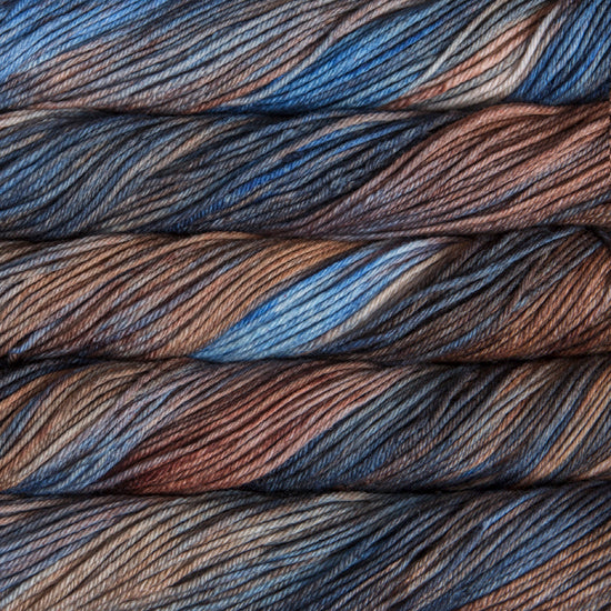 A close up of skeins of Malabrigo Rios worsted weight yarn in blue, beige and brown colors