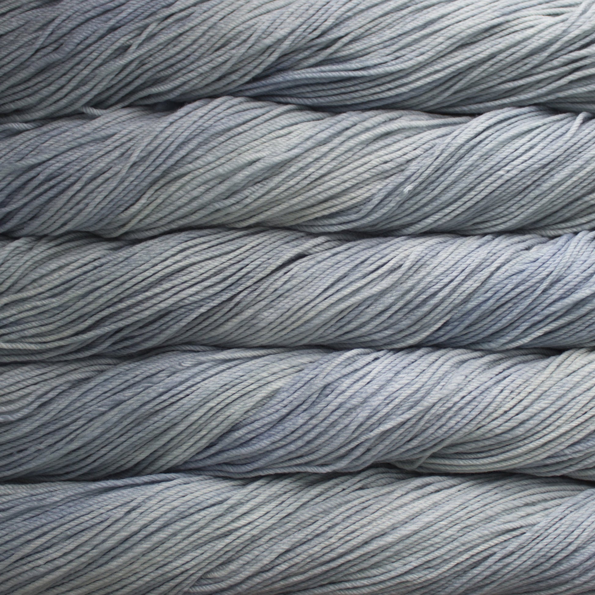 A close up of skeins of Malabrigo Rios worsted weight yarn in light grey color