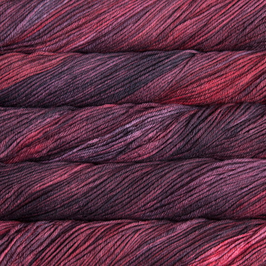 A close up of skeins of Malabrigo Rios worsted weight yarn in deep purple and pink colors