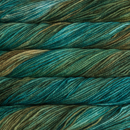A close up of skeins of Malabrigo Rios worsted weight yarn in deep aqua and beige colors
