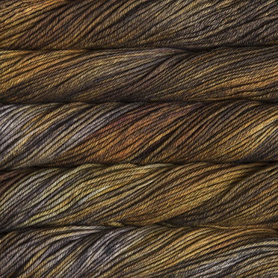 A close up of skeins of Malabrigo Rios worsted weight yarn in brown, yellow, and grey colors