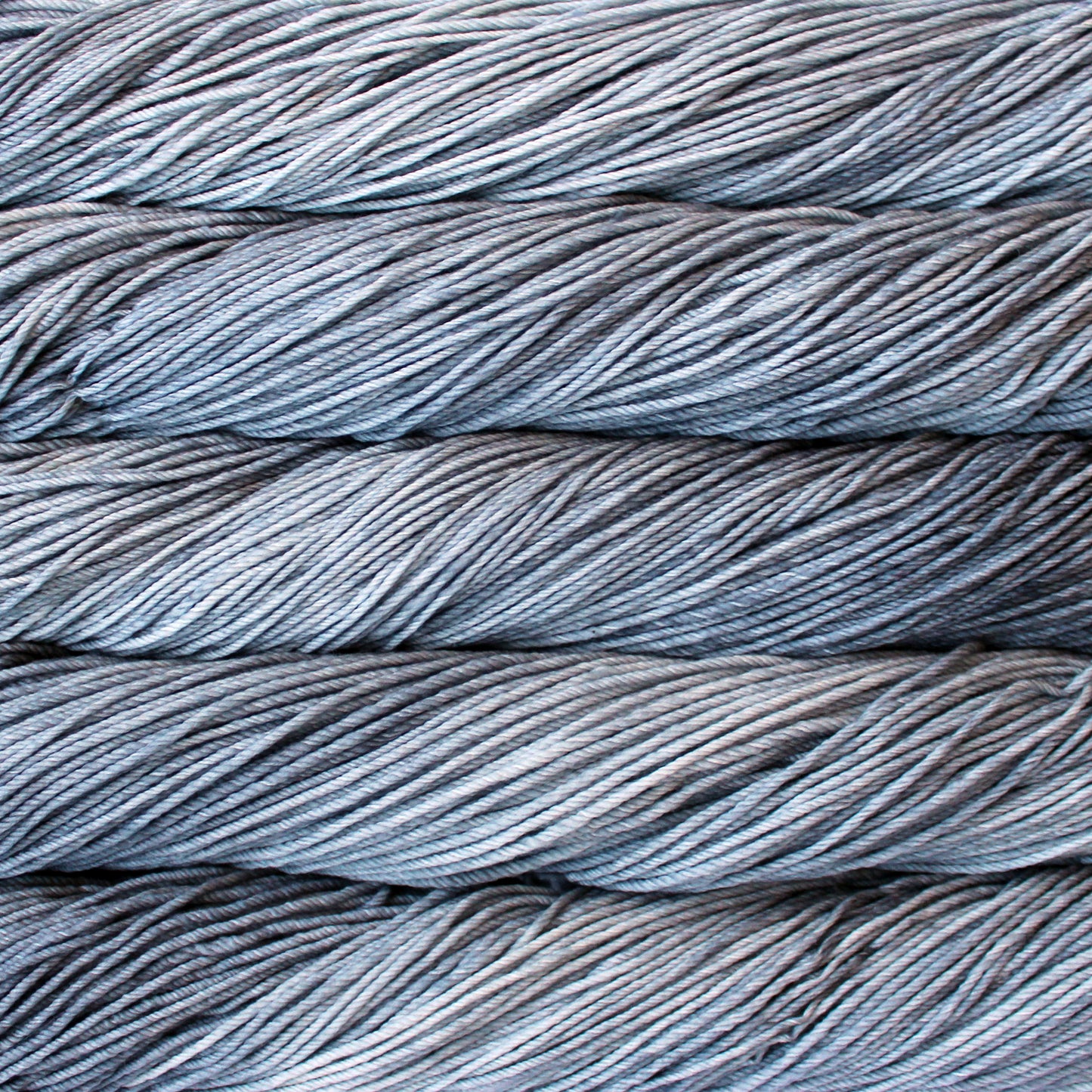 A close up of skeins of Malabrigo Rios worsted weight yarn in light and ark grey color