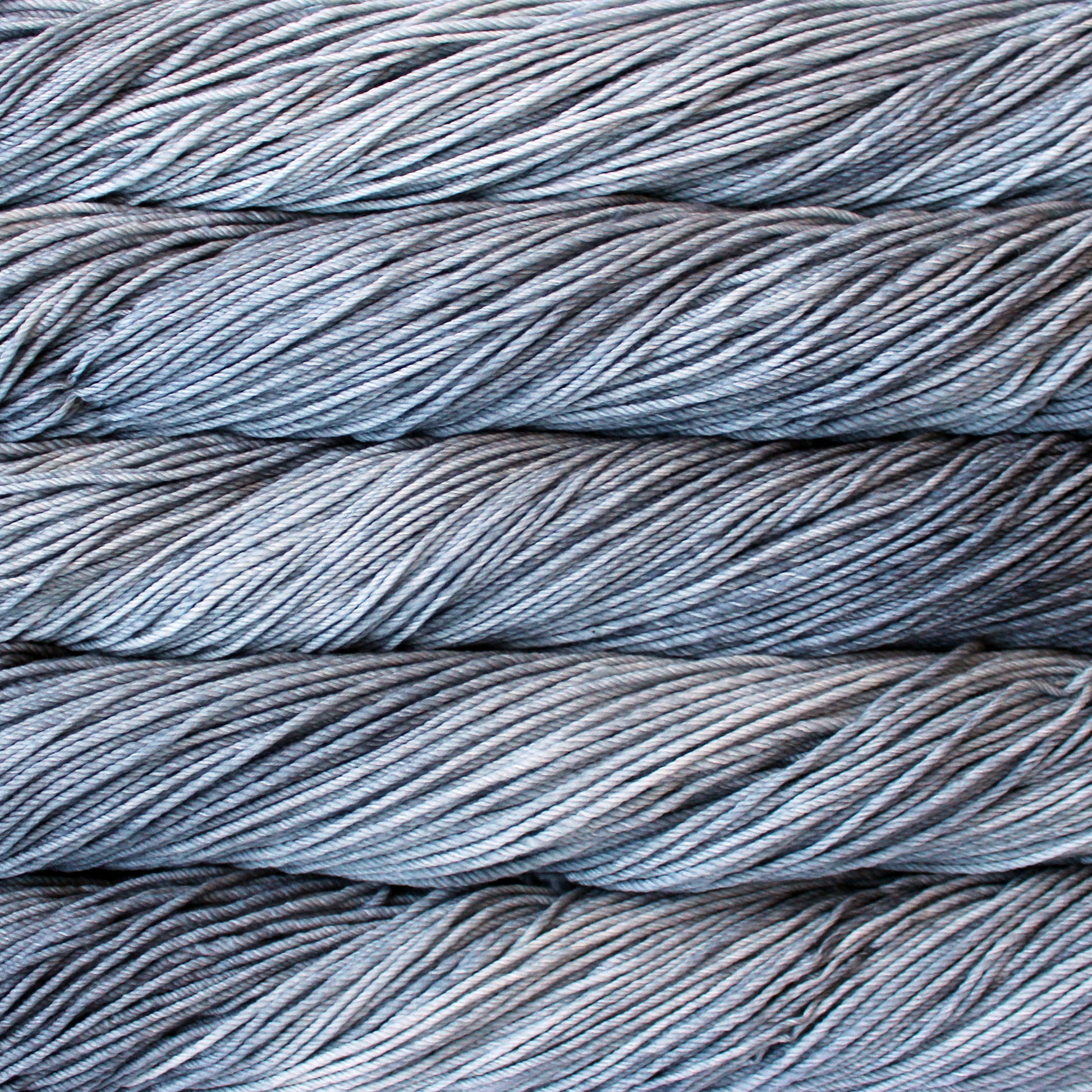 A close up of skeins of Malabrigo Rios worsted weight yarn in light and ark grey color