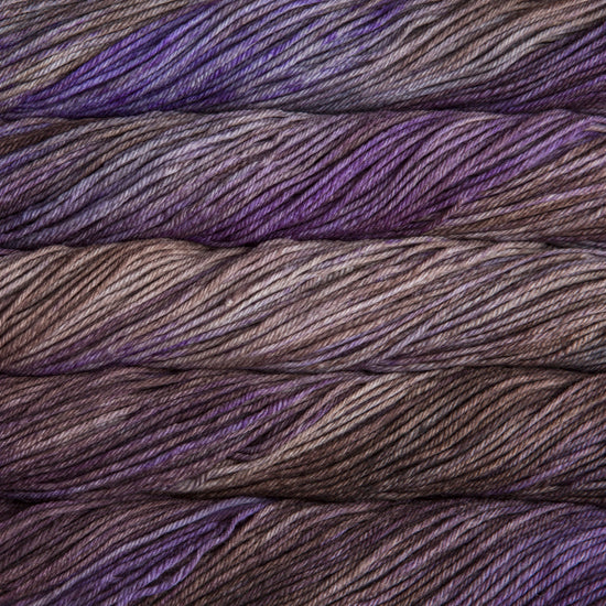 A close up of skeins of Malabrigo Rios worsted weight yarn in purple, beige, and brown colors