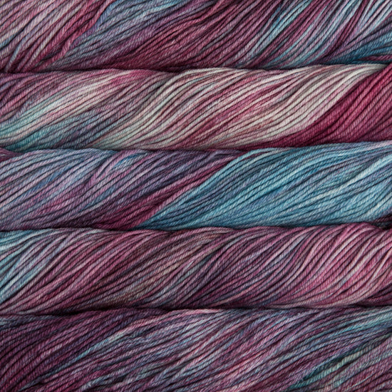 A close up of skeins of Malabrigo Rios worsted weight yarn in mauve, purple, blue, and beige colors