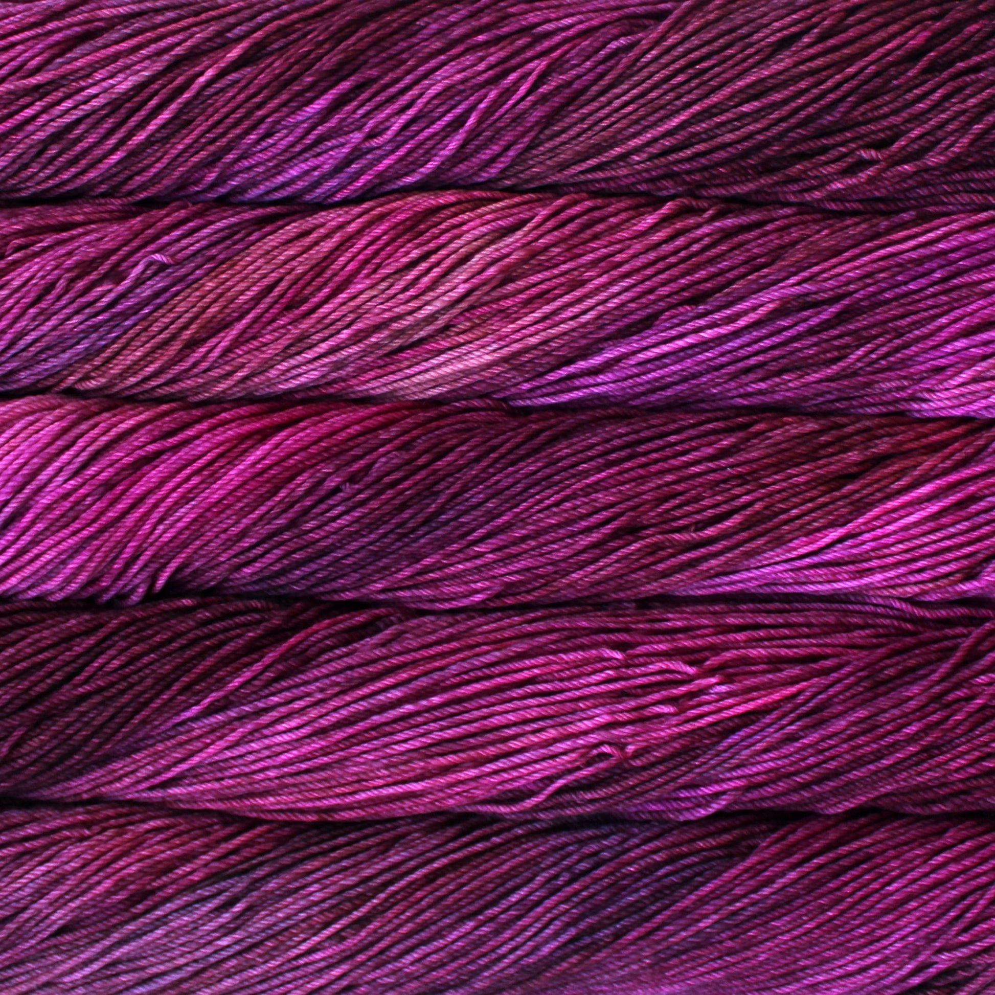 A close up of skeins of Malabrigo Rios worsted weight yarn in pink, mauve, and purple colors