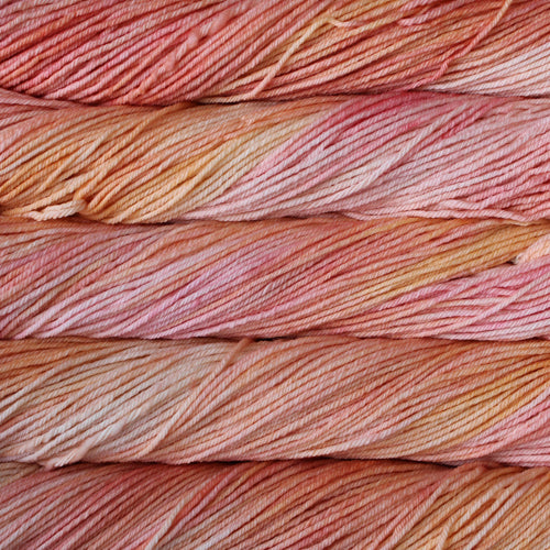 A close up of skeins of Malabrigo Rios worsted weight yarn in light pink and orange colors