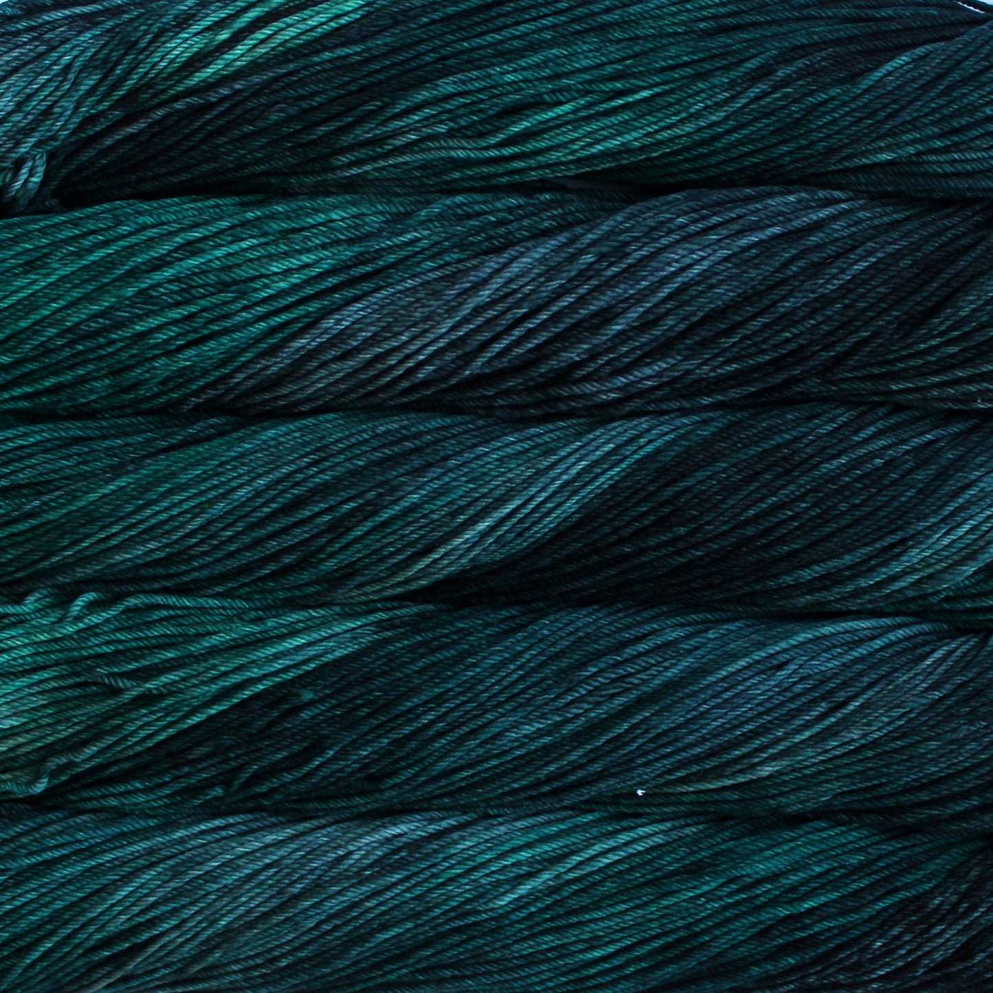 A close up of skeins of Malabrigo Rios worsted weight yarn in dark green and teal colors