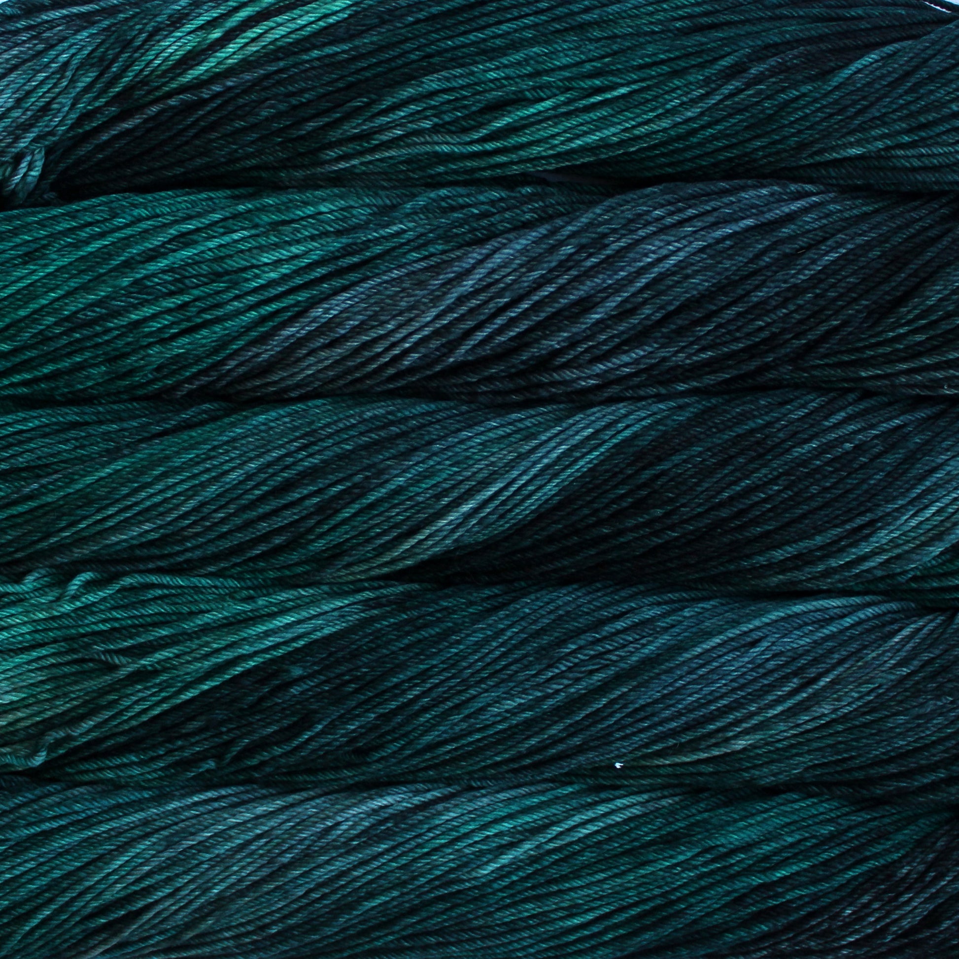 A close up of skeins of Malabrigo Rios worsted weight yarn in dark green and teal colors