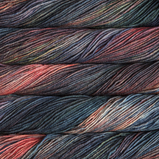 A close up of skeins of Malabrigo Rios worsted weight yarn in orange, blue, green, and grey colors