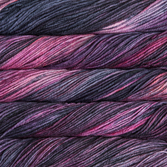 A close up of skeins of Malabrigo Rios worsted weight yarn in dark grey and pink colors