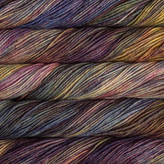 A close up of skeins of Malabrigo Rios worsted weight yarn in deep yellow, beige, blue, teal, and purple colors