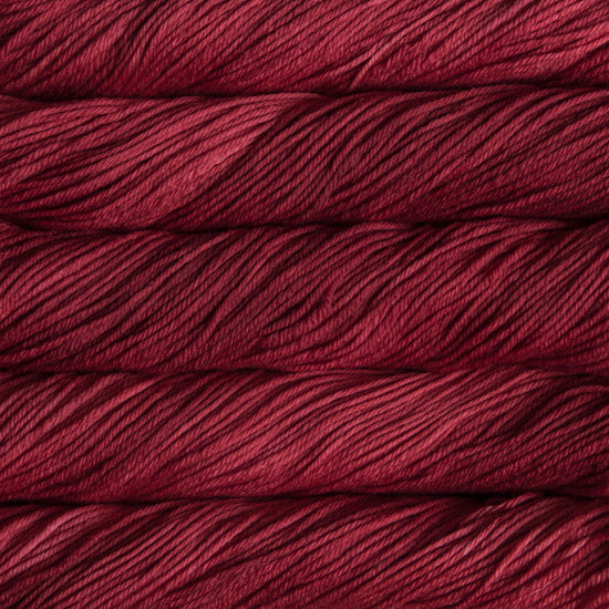 A close up of skeins of Malabrigo Rios worsted weight yarn in deep red color