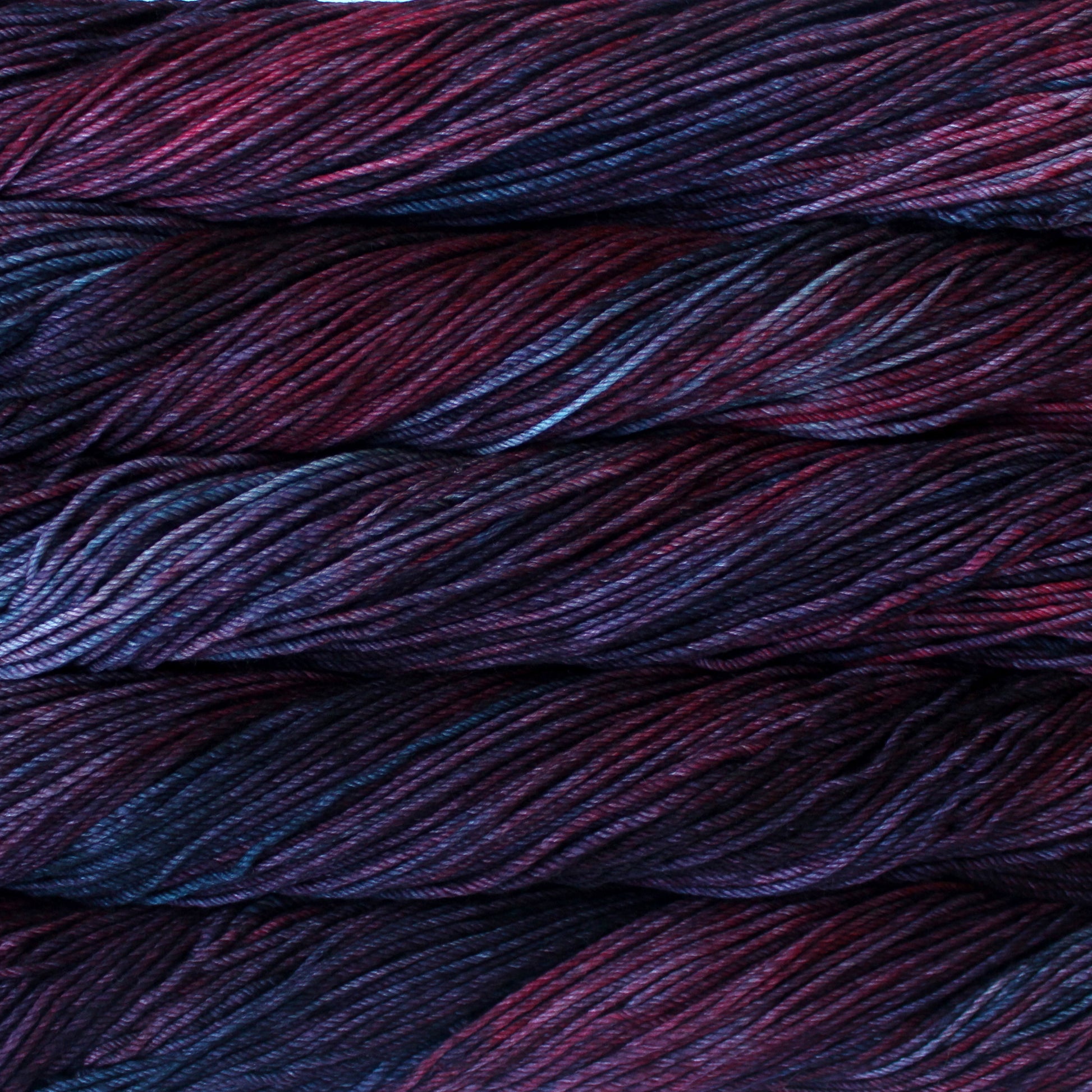 A close up of skeins of Malabrigo Rios worsted weight yarn in dark blue and red colors