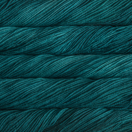A close up of skeins of Malabrigo Rios worsted weight yarn in deep teal green color