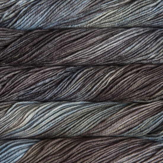 A close up of skeins of Malabrigo Rios worsted weight yarn in light and dark grey and brown colors